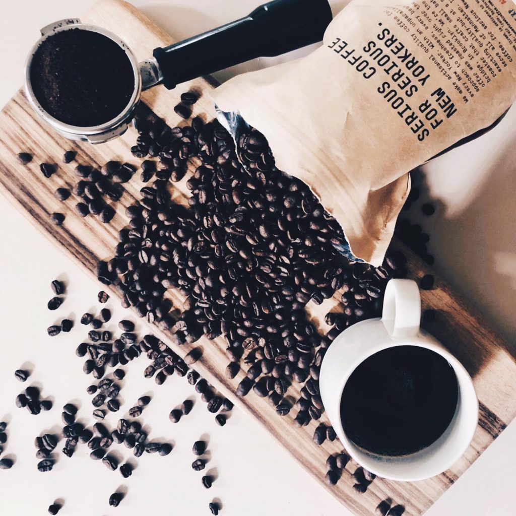 coffee beans spilled with coffee mug and portafilter