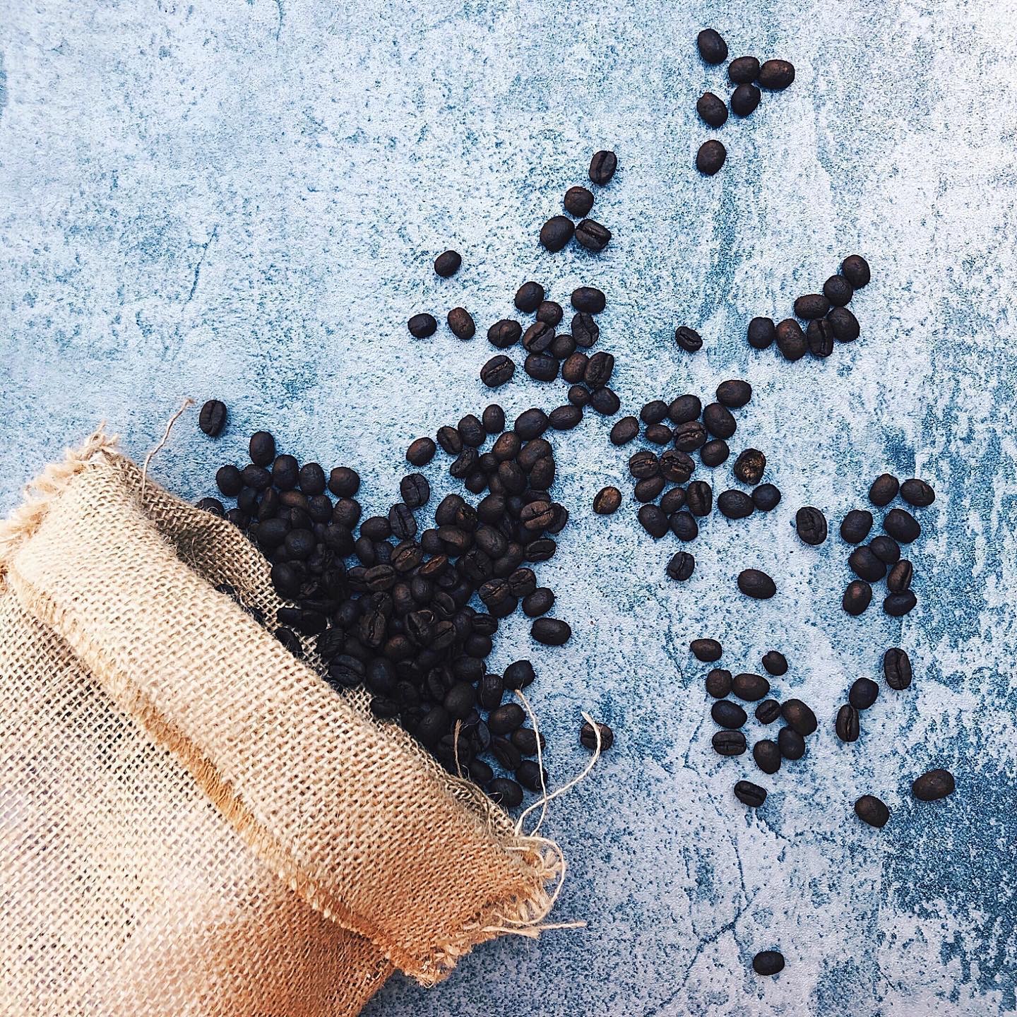 Coffee beans in burlap bag with blue background