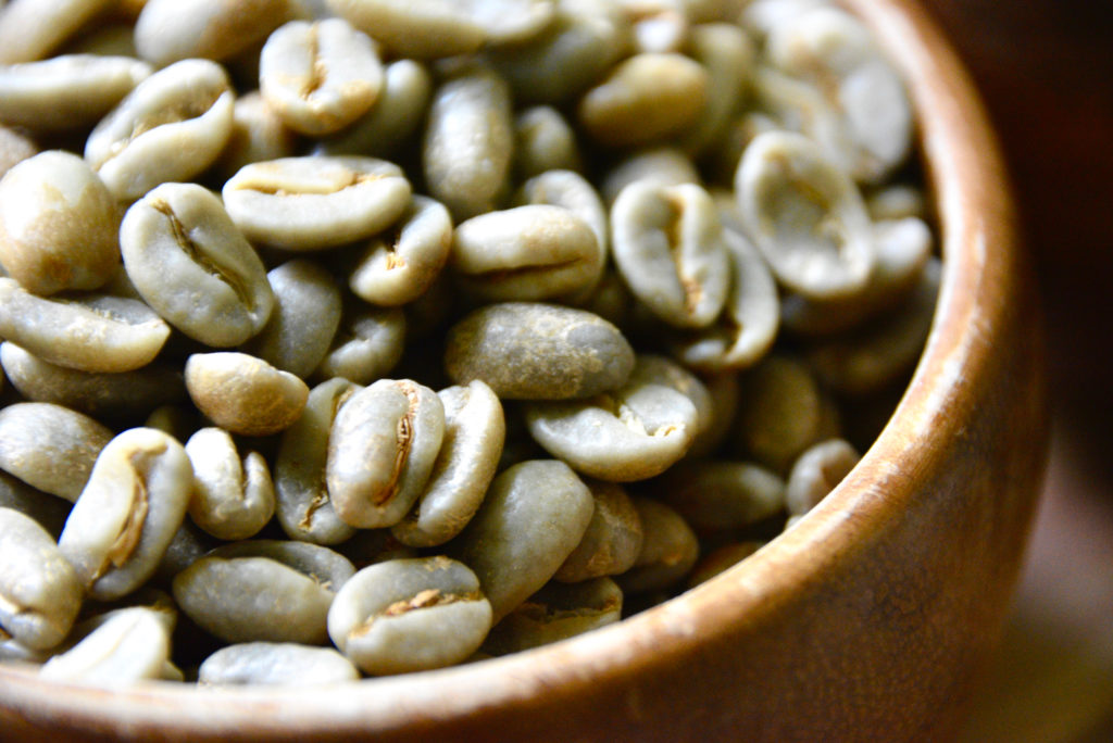 green coffee beans in a wooden bowl