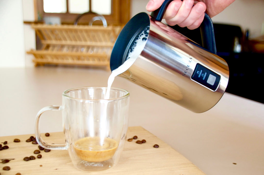 Milk frother pouring into a clear mug 