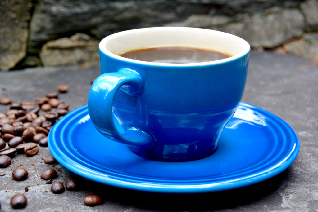 blue coffee cup with saucer on cement pavement
