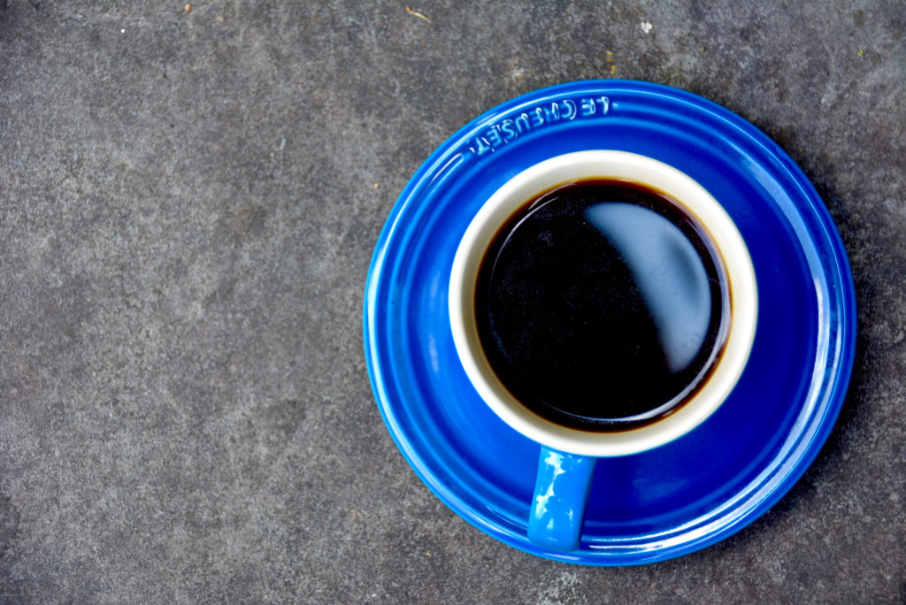 blue coffee cup with saucer on cement pavement
