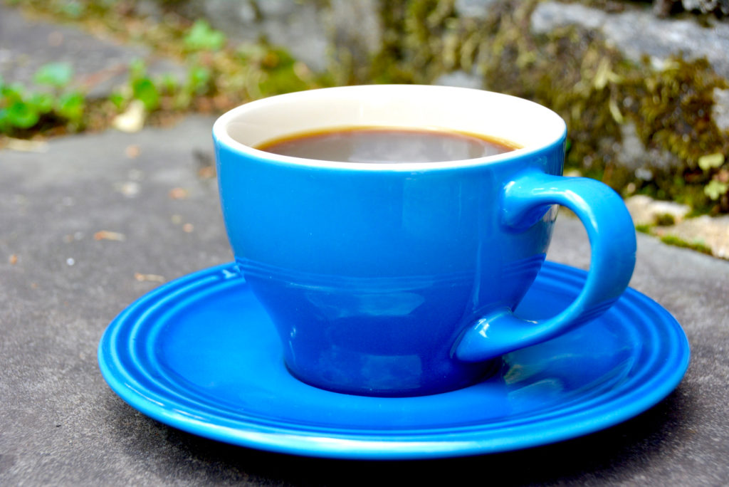 blue coffee cup with saucer on cement pavement