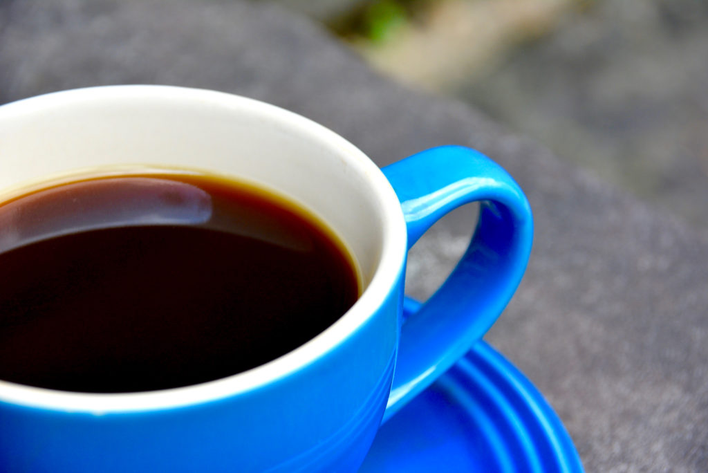 blue coffee cup with saucer on cement pavement