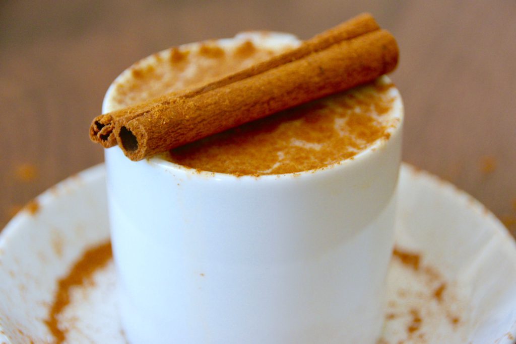 pumpkin spice latte in a white cup with a cinnamon stick