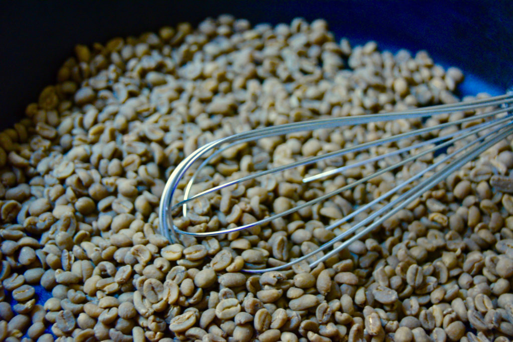 green beans in a cast iron skillet being stirred with a metal whisk 