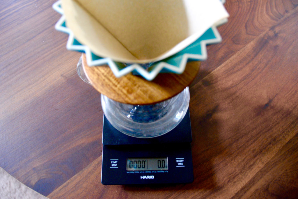 Origami pour over turquoise color on a hario scale on a wooden table 