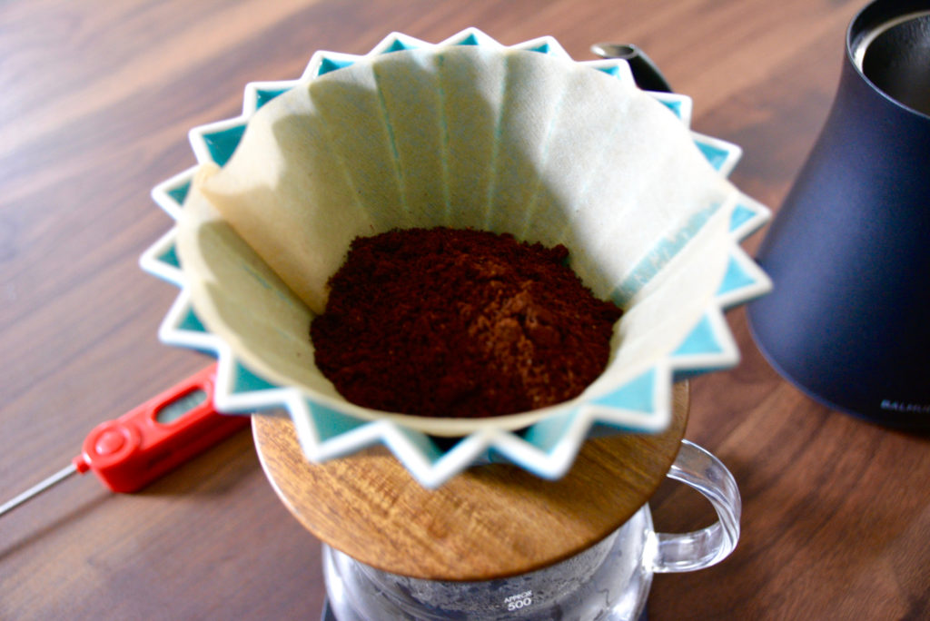 Origami pour over turquoise color on a wood table with a thermometer in background 