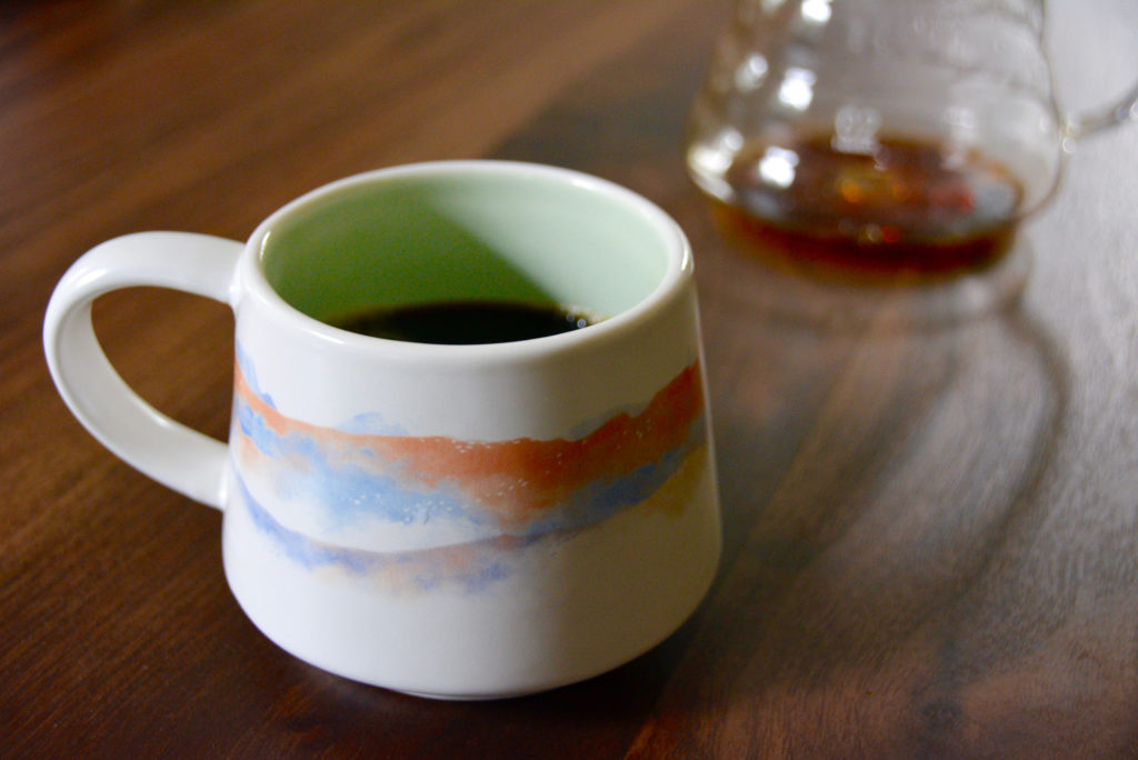 a white and pink and blue ceramic watercolor mug on a wooden table