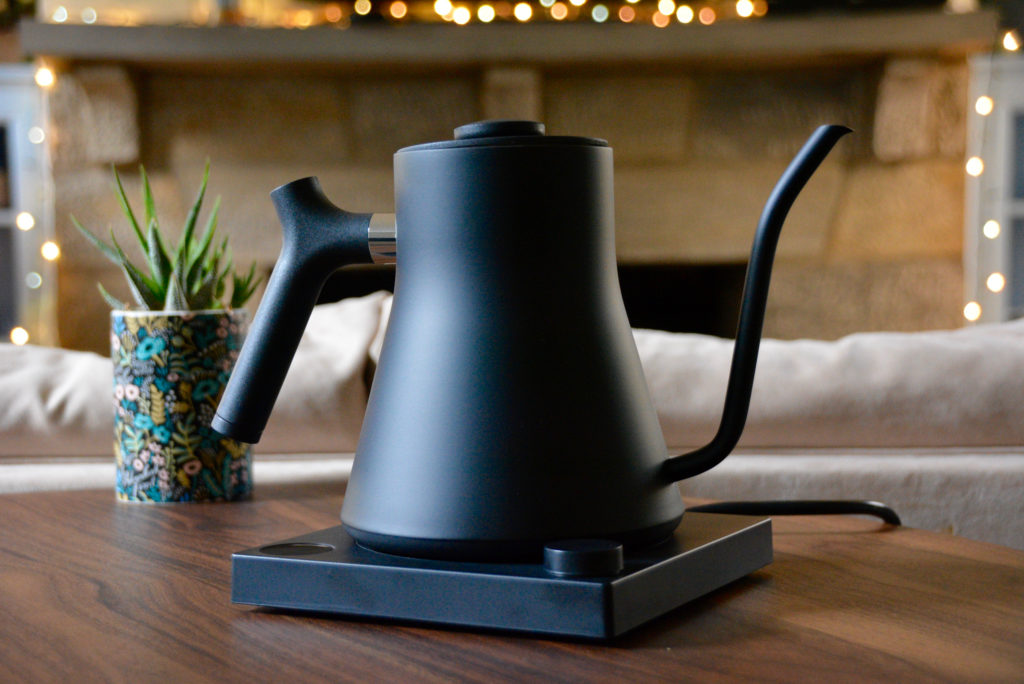 the Fellow gooseneck kettle in matte black with christmas lights in the background and a succulent