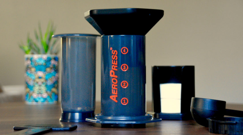 Aeropress separated into components sitting on a table with a succulent in background