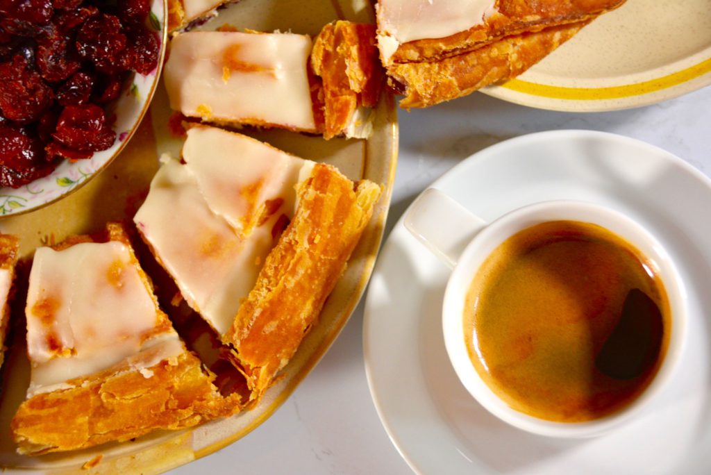 Overhead view of Wisconsin kringle and a cup of coffee on a table, styled as a cozy breakfast at home.
