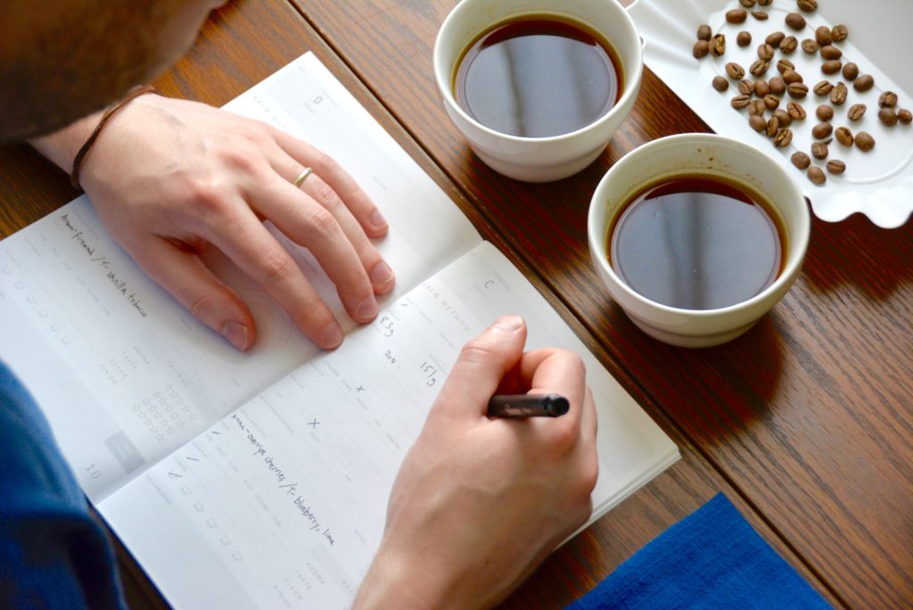 man writes in cupping form during a coffee cupping 