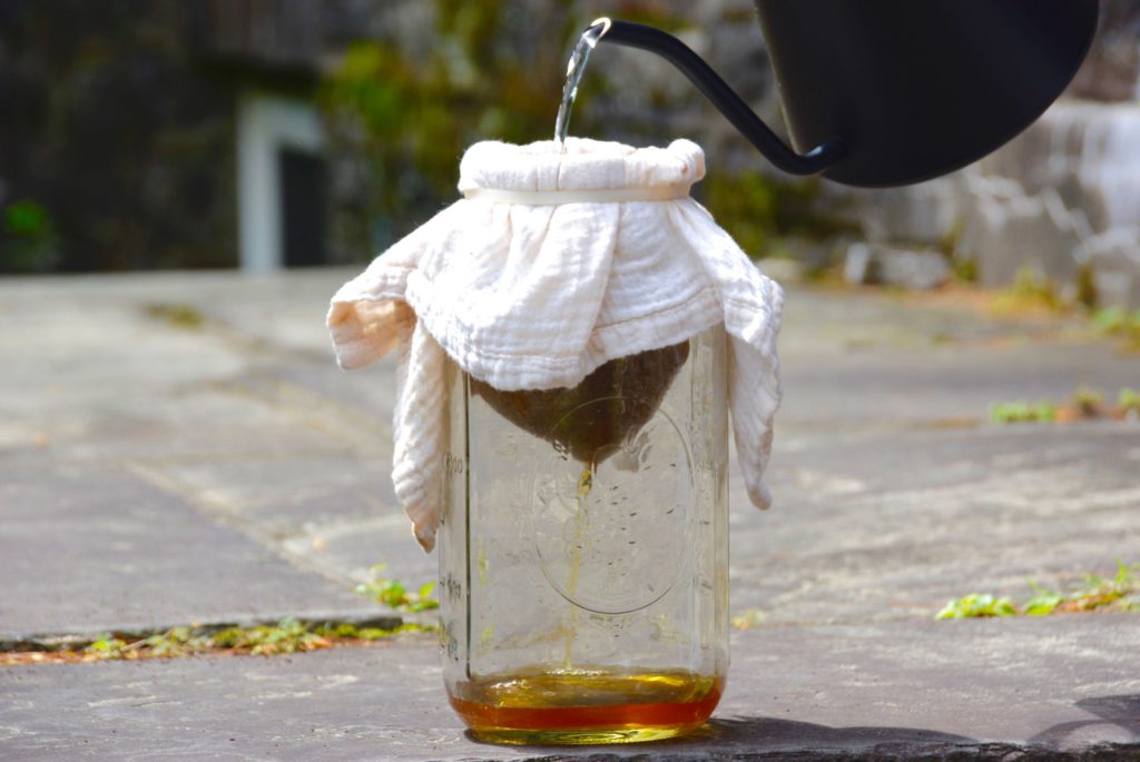 pouring water into a cheesecloth with coffee grounds