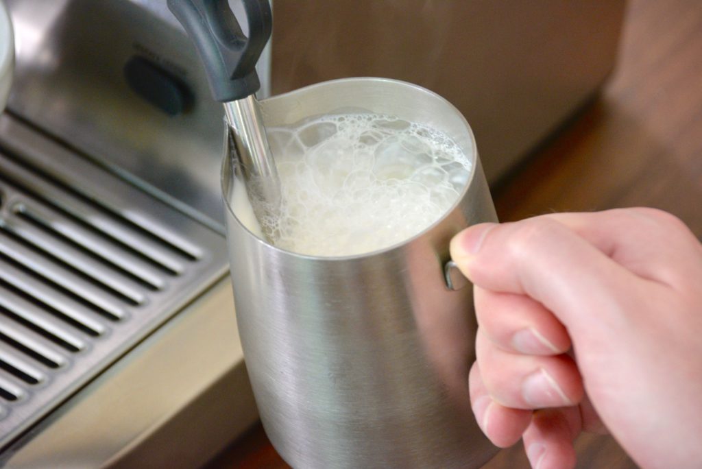 steaming milk with large bubbles at the top of milk pitcher