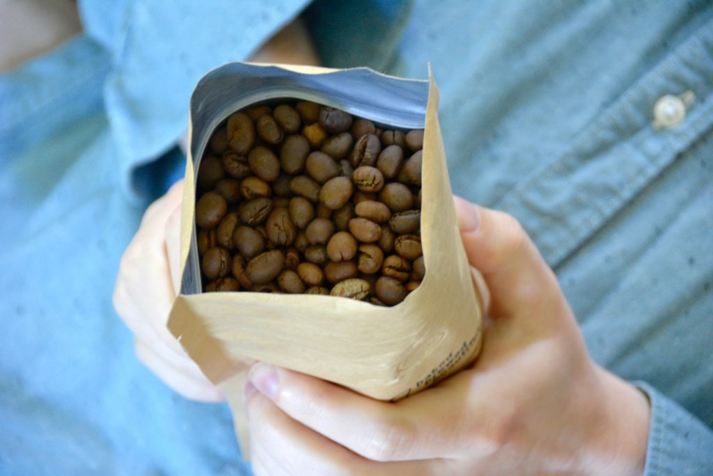 man holding bag of coffee beans on blue background 