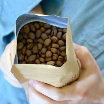 man holding bag of coffee beans on blue background