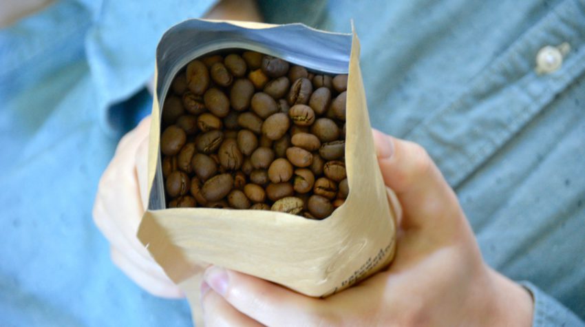 man holding bag of coffee beans on blue background