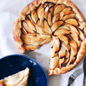 apple galette with a slice out of it on a blue plate next to it  