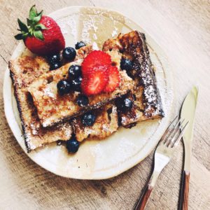 French toast with strawberries and blueberries on a light pink plate