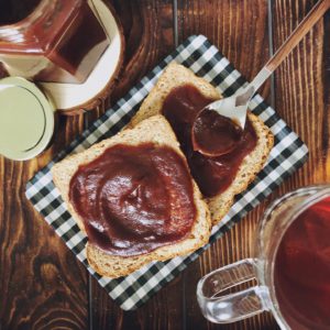 whole wheat bread with apple butter on a plaid plate and wood background 