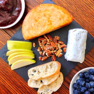 cheese plate with soft and hard cheese, fruits, nuts, and jam 