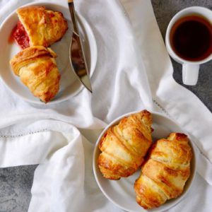 croissants on a white and blue background flat lay with cup of coffee