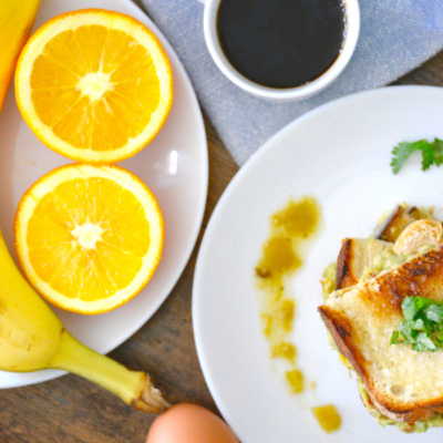 grilled cheese on white plate with coffee and banana and oranges