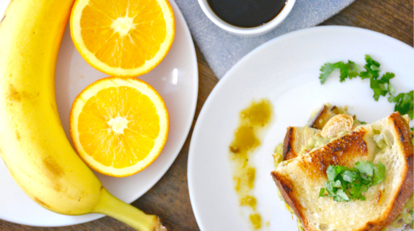 grilled cheese on white plate with coffee and banana and oranges