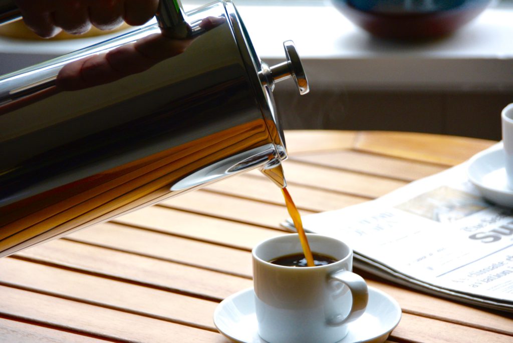 coffee being poured from a metal French press