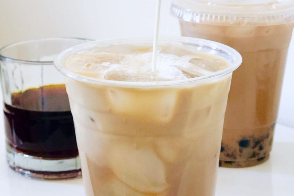 pouring milk into a boba coffee with ice