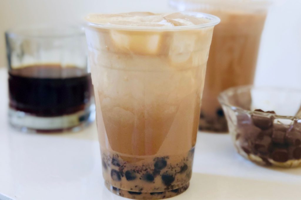 close up of boba coffee with tapioca balls in glass bowl on white background