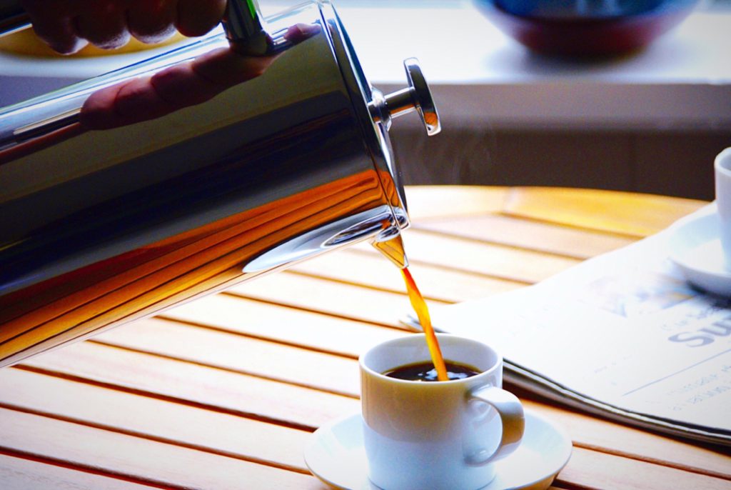 french press pouring coffee into a small white mug