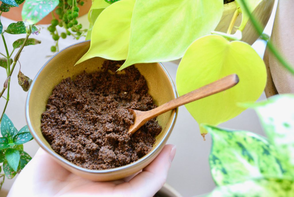 bowl of coffee grounds held in front of plants