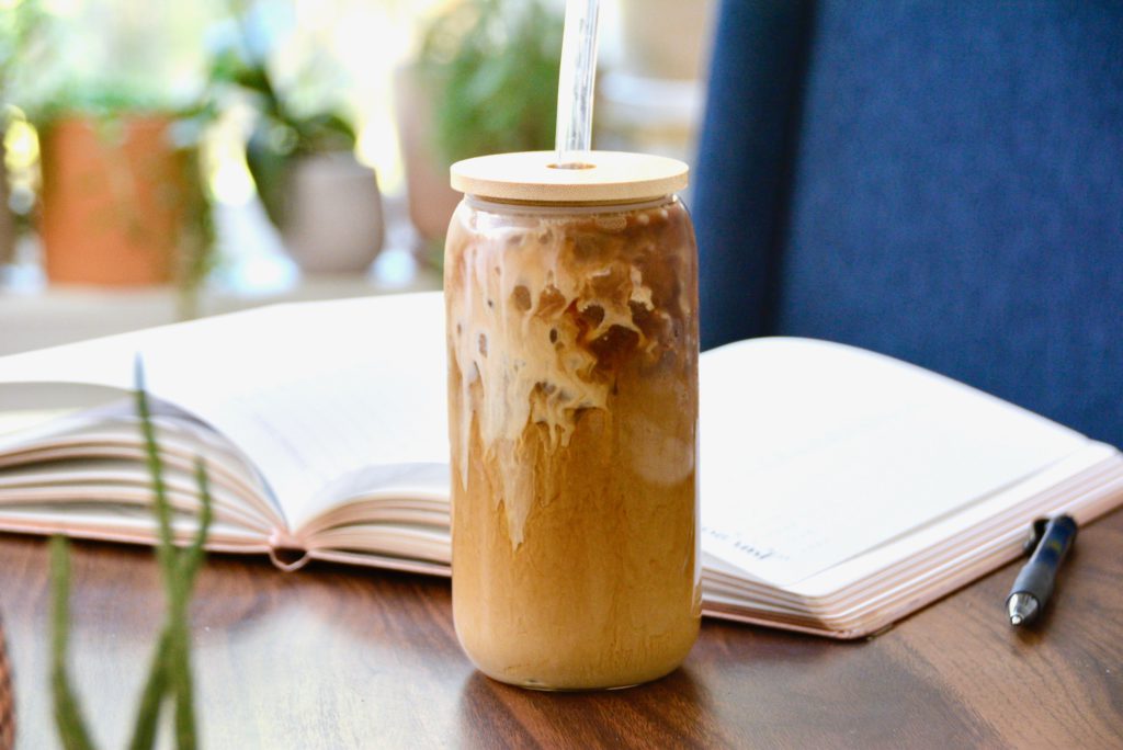 iced coffee with glass straw with a notebook on table